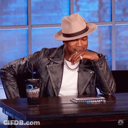 Man In Hat And Leather Jacket At Table With Cup And Notebook GIF