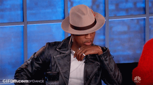 Man In Hat And Leather Jacket Sitting In Front Of NBC Logo GIF