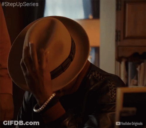 Man In Hat And Leather Jacket Sitting In Front Of YouTube Originals Sign GIF