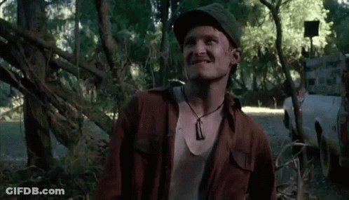 Man In Hat And Necklace Smiling In Woods GIF
