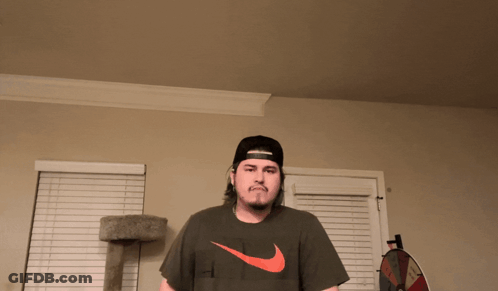 Man In Hat And Nike Shirt Near Cat Tree GIF