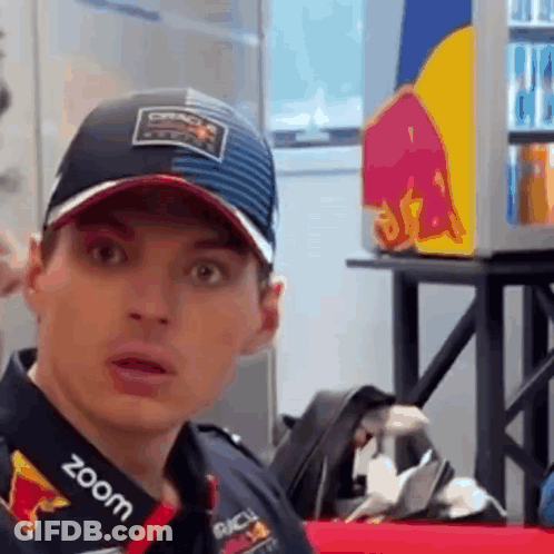 Man In Hat And Red Bull Shirt Looking At Camera GIF