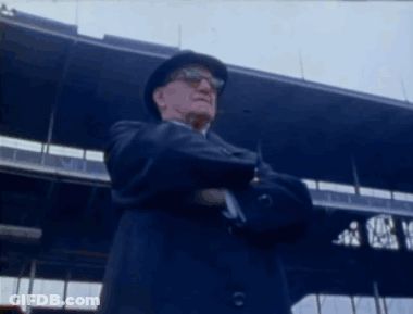 Man In Hat And Sunglasses Arms Crossed At Stadium GIF