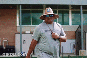 Man In Hat And Sunglasses Walking In Front Of Brooklyn Building GIF