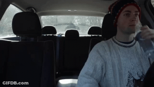 Man In Hat And Sweater Drinking Water In Back Seat GIF
