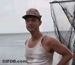 Man In Hat And Tank Top Standing By Fishing Net GIF