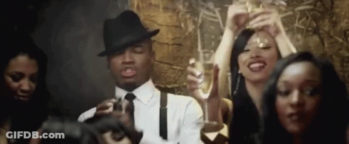 Man In Hat And Tie Holding Champagne In Crowd GIF