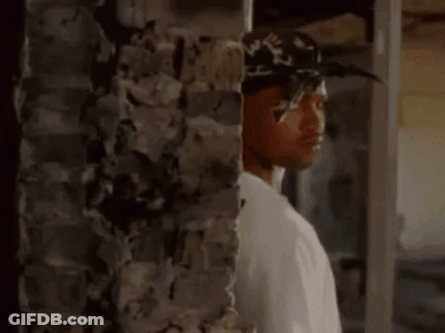 Man In Hat And White Shirt In Front Of Brick Wall GIF