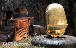 Man In Hat Covering Mouth Next To Golden Object GIF