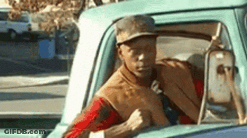 Man In Hat Driving Truck Down Street GIF