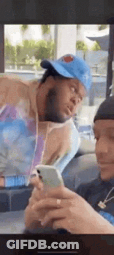 Man In Hat On Cell Phone, Another Man Watching GIF
