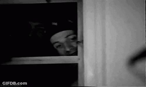 Man In Hat Peeking Out Window GIF