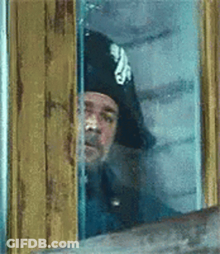 Man In Hat Peeking Out Window GIF