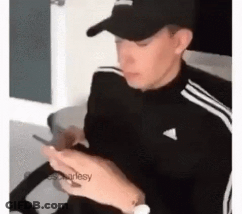 Man In Hat Sitting In Chair Looking At Phone GIF