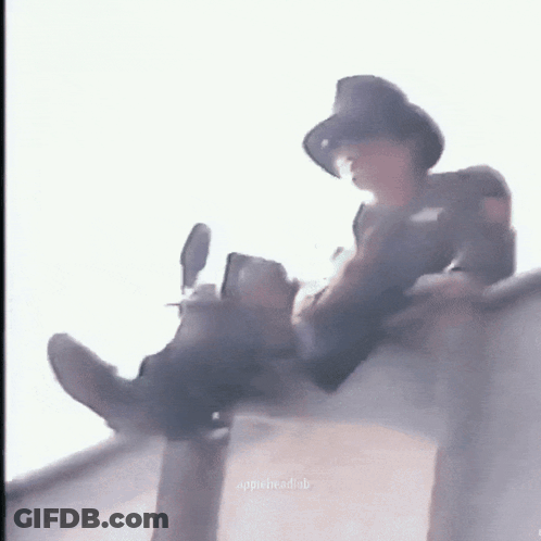 Man In Hat Sitting On Ledge With Legs Crossed GIF
