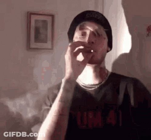 Man In Hat Smoking Cigarette In Living Room GIF
