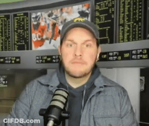 Man In Hat Standing At Microphone In Front Of Scoreboard GIF