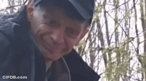 Man In Hat Standing Before Fence GIF