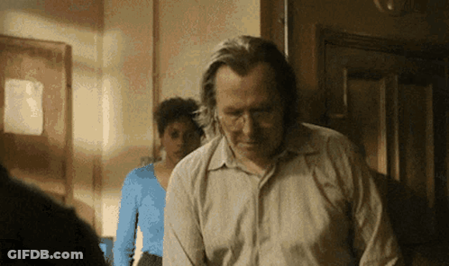 Man In Hat Standing In Front Of Agárrate Sign GIF