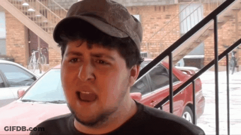 Man In Hat Standing In Front Of Brick Building GIF