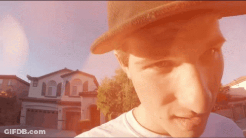 Man In Hat Standing In Front Of Large House GIF
