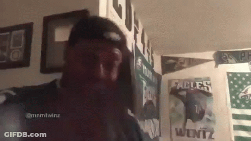 Man In Hat Standing In Front Of Poster Wall GIF