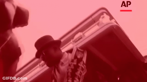 Man In Hat Standing Next To Briefcase With Letters AP GIF