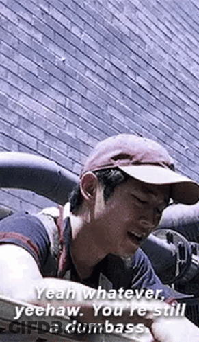 Man In Hat Talking In Front Of Brick Wall GIF