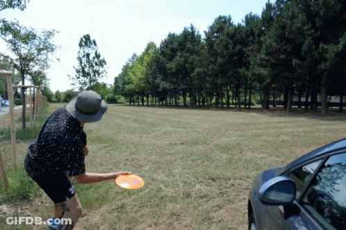 Man In Hat Throwing Frisbee In Grassy Field GIF