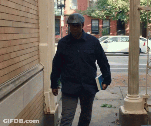 Man In Hat Walking Down Sidewalk GIF