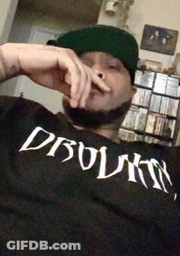 Man In Hat Wearing Dbolmn Shirt Smoking Cigarette GIF