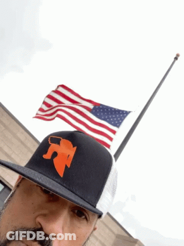 Man In Hat With Letter R In Front Of Flag GIF
