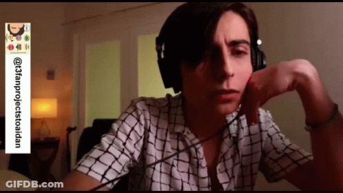Man In Headphones And Plaid Shirt Sitting At Desk GIF