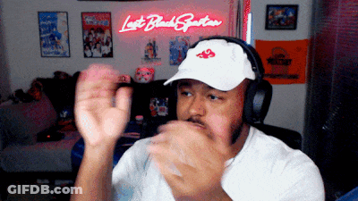 Man In Headphones And White Hat In Front Of Lost Black Spartan Neon Sign GIF