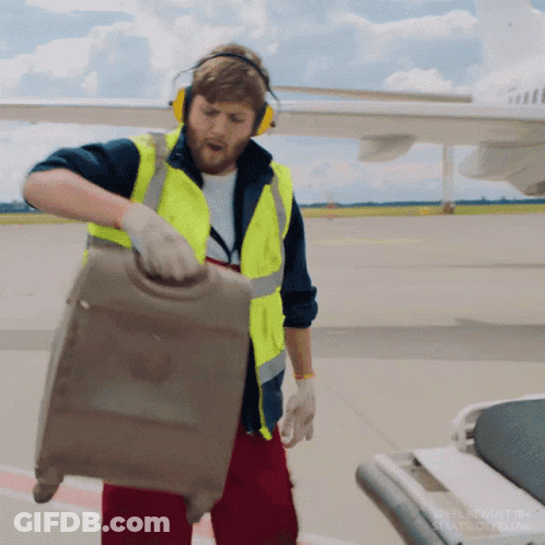 Man In Headphones And Yellow Vest Pulling Suitcase GIF
