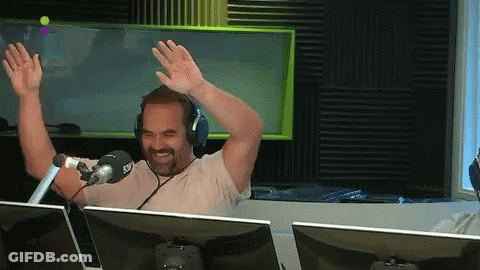 Man In Headphones Sitting At Microphone With Hands Up GIF