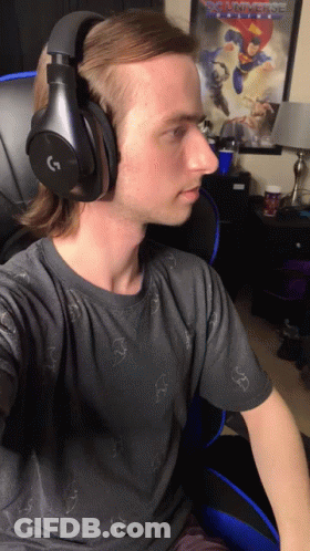 Man In Headphones Sitting In Front Of Justice League Poster GIF