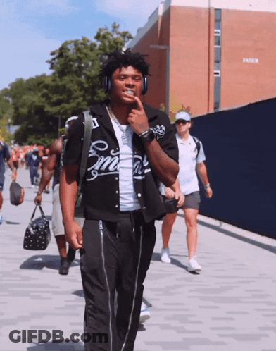 Man In Headphones Wearing Smith Shirt Walking Down Street GIF