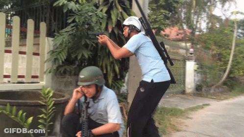 Man In Helmet Holding Gun With Another Man Looking On GIF