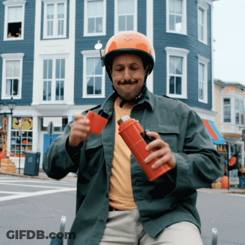Man In Helmet Holding Red Bottle In Front Of Building GIF