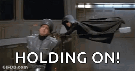 Man In Helmet Holding Woman In Cape GIF