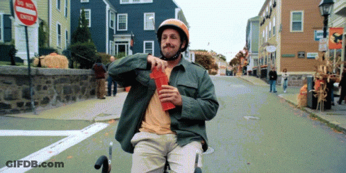 Man In Helmet Riding Scooter Down Street GIF