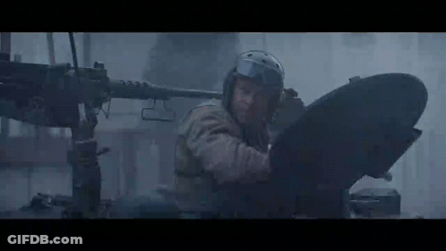 Man In Helmet Standing In Front Of Machine Gun In Dark Room GIF