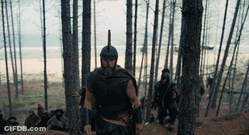 Man In Helmet With Spear Walking Through Forest GIF