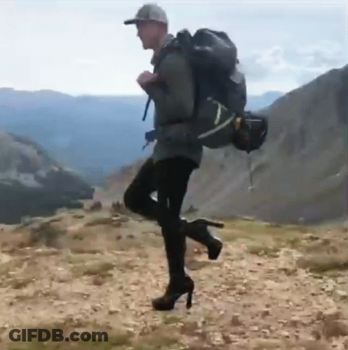 Man In High Heels And Backpack On Hill GIF
