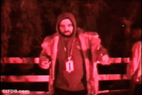 Man In Hooded Jacket By Fence In Dark Room GIF