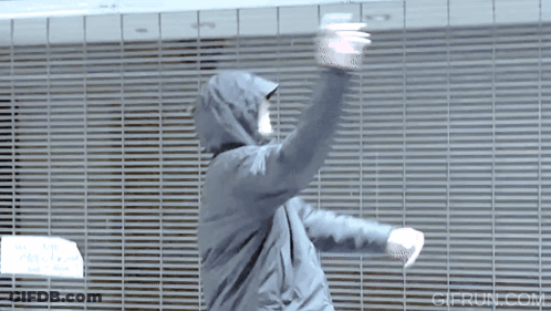Man In Hooded Jacket Dancing In Front Of Grid Wall GIF