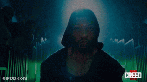 Man In Hooded Jacket Standing In Front Of Crowd GIF