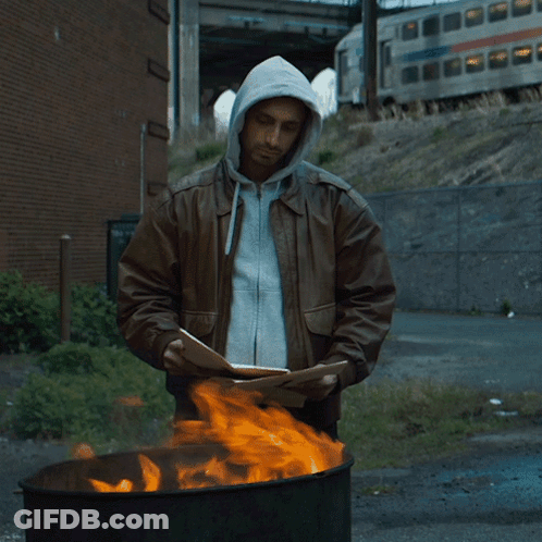 Man In Hooded Jacket Standing In Front Of Fire GIF