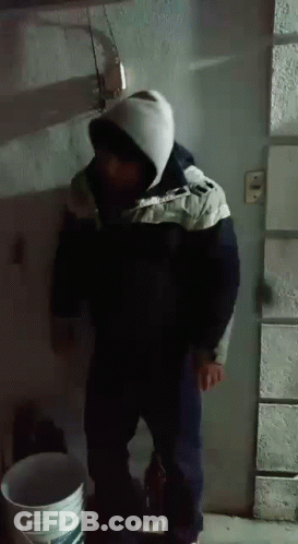 Man In Hooded Jacket Standing Next To Bucket GIF